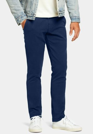 Marineblaue Chinohosen aus Baumwollmischung, schmale Passform, mit zwei seitlichen Taschen und kombiniert mit weißen Sneakers für einen Kontrast.