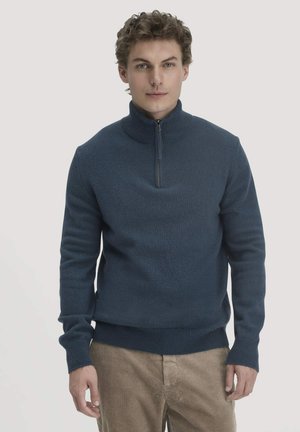 Navyblauwe trui met rits in een textuur breisel, met geribde manchetten en zoom, gecombineerd met beige corduroy broeken.