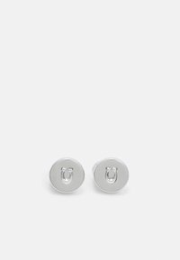 Pendientes de botón redondos de plata con un detalle de herradura elevado en el centro, acabado pulido y textura de metal suave.