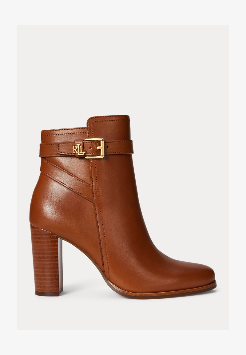 Ruda odinė kulkšnies avalynė su aukštu stacked kulnu, šoniniu sagties dirželiu su auksiniu RLL logotipu ant vienspalvio fono.