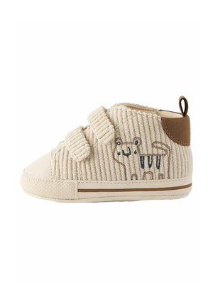 Baskets beige pour tout-petits avec texture en velours côtelé, deux bandes Velcro, languette marron et tigre de dessin animé brodé sur le côté.