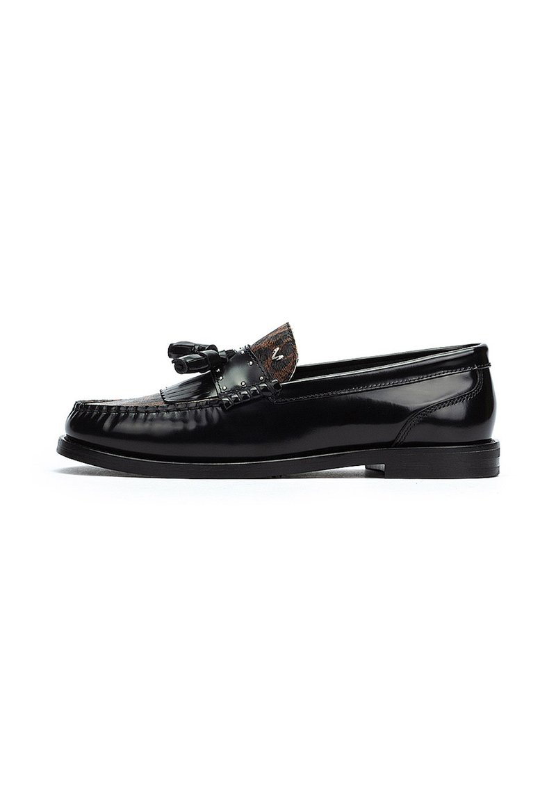 Mocassins en cuir noir avec un bout arrondi, présentant un nœud décoratif et un accent texturé au niveau de l'empeigne. Fini lisse et brillant avec un talon bas.