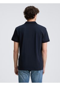 Marineblå kortærmet polo t-shirt med klassisk krave og ribbede detaljer, lavet af et glat, åndbart stof. Bagsiden vises.