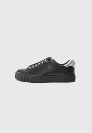 Niedriger schwarzer Ledersneaker mit silbernem Fersenakzent, perlenähnlichen Ösen und dicker schwarzer Gummisohle auf hellgrauem Hintergrund.