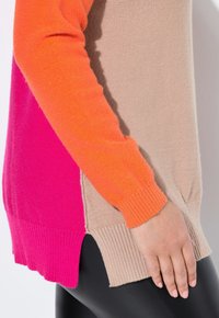 Maglione a blocchi di colore con sezioni arancioni, rosa e beige. Materiale morbido, polsini e fondo a costine, con una leggera apertura laterale.