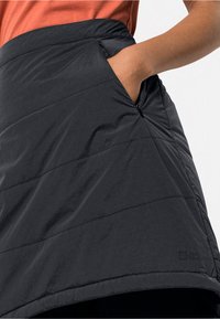 Zwarte geïsoleerde rok met diagonaal gestikt patroon, zijzak en elastische tailleband. Gladde textuur en lichtgewicht ontwerp, geschikt voor buitengebruik.