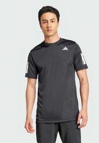 Črna športna majica iz tkanine, ki odvaja vlago. Ima kratke rokave in bel logotip Adidas na levem prsnem košu ter na rokavu.