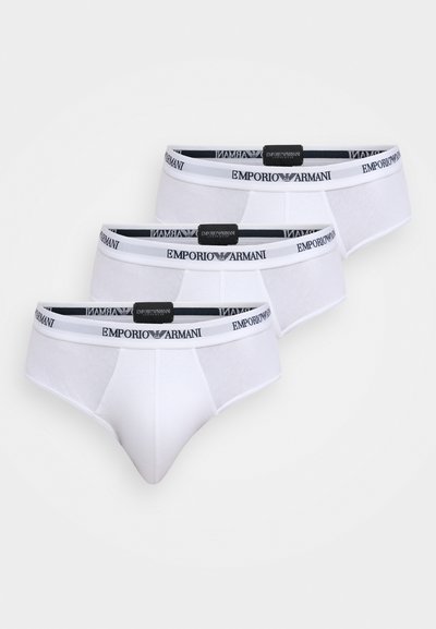 Culottes blanches en coton avec une coupe ajustée et une ceinture élastique portant le logo "Emporio Armani". Trois paires sont affichées.