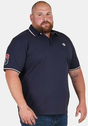 Polo en navy en coton, avec un col et des manches rayés blancs et rouges, un corps sans embellissement et un logo sur la poitrine gauche.