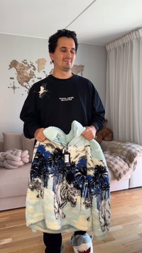 Plišasta odeja z modrim in svetlo zelenim vzorcem tigra in palm. Mehka tekstura, z ruto in sprednjim žepom, nova z obeskom za ceno.