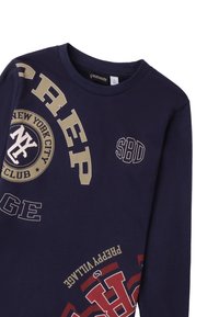 Marineblaues Langarmshirt mit goldenen Grafiken. Enthält Text und Embleme, darunter "NEW YORK CITY CLUB" und "SBD". Aus weichem Baumwollmaterial.