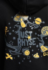 Sort hættejakke med farverigt grafisk design, der inkluderer gule og sølvsvampe, rumvæsener, stjerner og teksten "JUST RHYSE."