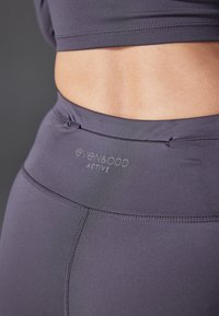Legginsy sportowe z wysokim stanem w ciemnoszarym kolorze o gładkiej fakturze. Posiadają logo "even&odd ACTIVE" na pasku.