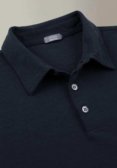 Polo-shirt marine en coton glace, avec un col classique, une patte de boutonnage à deux boutons et une texture lisse sans motifs visibles.