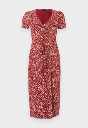 Robe midi rouge avec des taches blanches abstraites, manches courtes, décolleté en V, ceinture à la taille et trois boutons en bois sur le côté gauche.