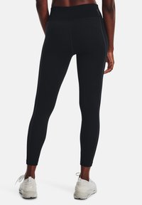 Leggings neri con un motivo testurizzato, vita alta e cuciture laterali a contrasto. Indossati con scarpe da ginnastica bianche.