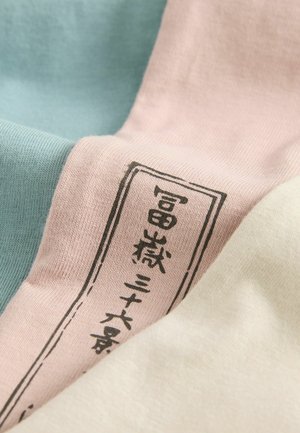 Tissu en coton dans des nuances de bleu clair, rose doux et crème ; présente un tissage texturé et une étiquette noire imprimée sur la partie rose.