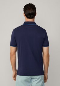 Marinblå polo med en kontrasterande ljusblå krage och ärmdetaljer, med en slät yta och korta ärmar.