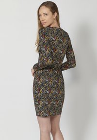 Sukienka bodycon z ciemnego materiału z multikolorowym wzorem kwiatowym. Długie rękawy, okrągły dekolt, dopasowany krój, długość do połowy uda.