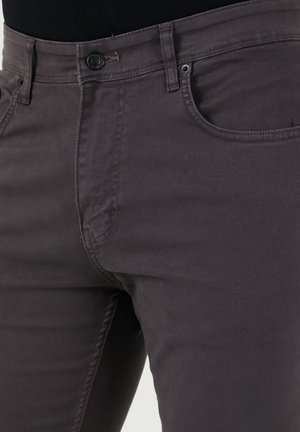 Bledě šedé džíny z denimu mají přiléhavý design, standardní pět kapsový styl a zapínání na knoflík s viditelnými švy.