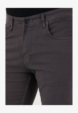 Vervagende grijze denim jeans hebben een fitted ontwerp, standaard vijf-pocket stijl en een knoopsluiting met zichtbare stikdetails.