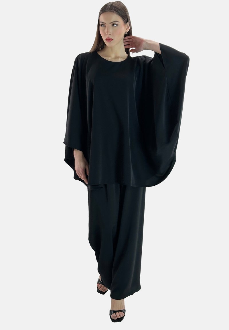 Schwarzes Zweiteiler-Outfit mit einem fließenden Oberteil mit weiten Ärmeln und locker sitzenden Hosen, gefertigt aus einem glatten Stoff mit einem sanften Glanz.