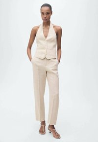 Beige linen halter vest with buttons paired with matching tailored pants; features a smooth texture and straight leg design.