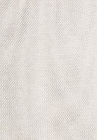 Vaaleanbeige neulottu kangas, jossa on sileä pinta. Koko kangas on tasaisesti kuvioitu ja siinä on tasaiset silmukat, mikä antaa pehmeän ulkonäön.