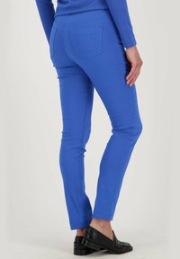 Heldere blauwe slim-fit broeken gemaakt van stretchstof, met gestikte details en een achterzak met een logo-accent. Gestyled met zwarte instappers.
