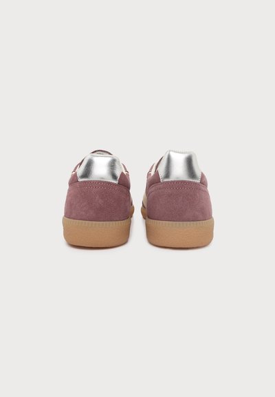 Paire de baskets en daim violet avec languettes argentées au talon et semelles en gomme naturelle, vues de dos sur un fond blanc uni.
