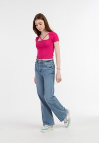 Top roz ajustat cu decolteu pătrat și bretele încrucișate, asortat cu blugi largi de culoare albastru deschis și adidași pastel.