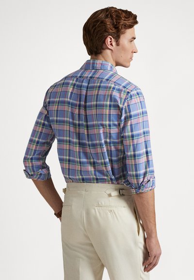 Herrskjorta i rutigt mönster med blå, rosa och gröna toner, med uppkavlade ärmar, klassisk krage och en avslappnad passform, matchad med ljusa byxor.