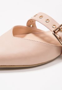 Bailarinas de cuero rosa claro con punta afilada y diseño de corte, que cuentan con una correa con remaches dorados y un acento de hebilla.