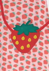 Bawełniana odzież z różowym tłem, zdobiona powtarzającymi się czerwonymi truskawkami oraz wyraźną aplikacją 3D w kształcie truskawki z żółtymi nasionami i zielonymi liśćmi.