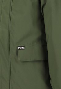 Groene, waterdichte jas met een gladde textuur, voorzien van een voorzak en een label "READY SET GO". Klassiek ontwerp, veelzijdig voor verschillende settings.