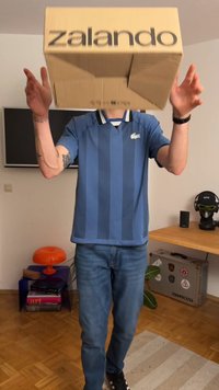 Zila vertikālais svītrotais Lacoste polo krekls ar apkakli, kombinēts ar gaišām džinsām. Brūna kartona kaste ar uzrakstu "zalando" tiek turēta virs galvas.