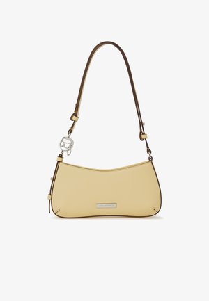 Kleine beige schoudertas met dunne bruine riem, zilveren logoplaatje en decoratieve zilveren bedel bevestigd aan de riemlus.