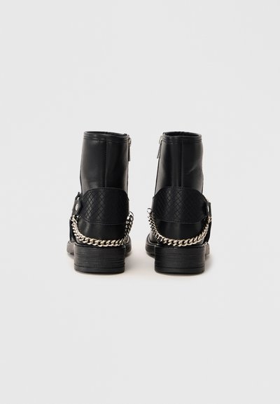 Stivaletti neri in pelle con design cucito, tacco texturizzato e una decorativa catena d'argento sul retro. Chiusura con zip su entrambi i lati.