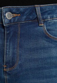Jeans in denim con un lavaggio blu scuro, cuciture visibili in arancione, chiusura con bottone in metallo e un classico design a cinque tasche.