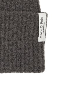 Beanie grigio in maglia con texture a coste. Presenta un piccolo etichetta bianca con la scritta "Marc O'Polo" stampata in nero. Il materiale sembra morbido e caldo.