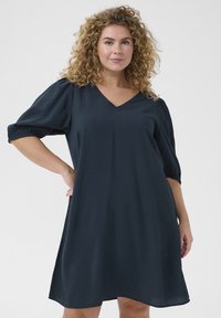 Vestido azul marino con escote en V y mangas cortas abullonadas, hecho de tela texturizada, con un corte suelto y una silueta fluida.