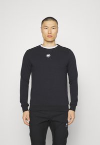 Felpa nera da uomo con collo a giro. Presenta un piccolo logo bianco sul petto, polsini a costine e tessuto strutturato. Abbinato a pantaloni neri.