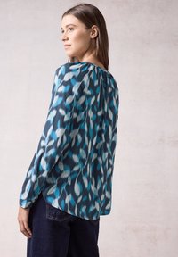Blusa a maniche lunghe blu e verde mare con motivo, dal taglio morbido, con scollatura rotonda e una leggera lunghezza asimmetrica.