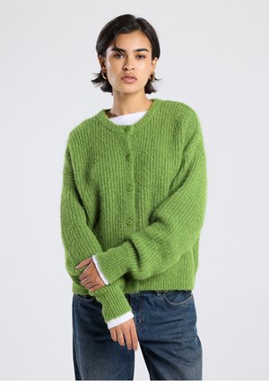 Groene gebreide cardigan met een geribbelde textuur, zeven knopen en lange mouwen. Witte manchetten die onder de mouwen uitkomen. Casual pasvorm.