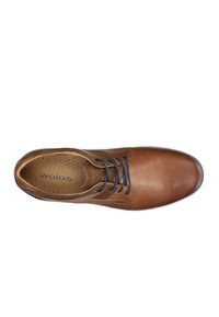 Scarpa stringata in pelle marrone con finitura liscia, punta tonda e lacci marrone scuro. Presenta una soletta perforata con il logo "wojas".