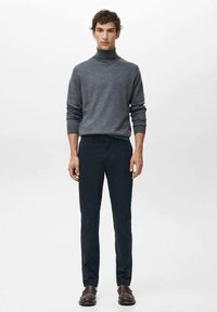 Mörkgrå polotröja, figursydd design, kombinerad med slim fit mörka byxor och bruna läderskor. Enkla, släta texturer och rena linjer.