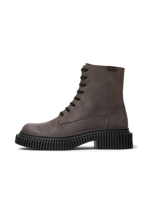 Botas de cuero marrón hasta el tobillo, con punta redonda, cordones en la parte delantera y suela de goma negra acanalada. Presenta un logo de Camper en el lateral.