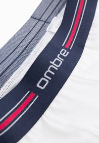 Herrboxershorts i vit tyg med en marinblå midja prydd med röda och vita ränder samt varumärket "ombre."