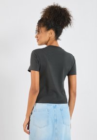 Svart t-skjorte med korte ermer og rund hals, tettsittende design, glatt tekstur, kombinert med en lyseblå denimskjørt med baklommer.