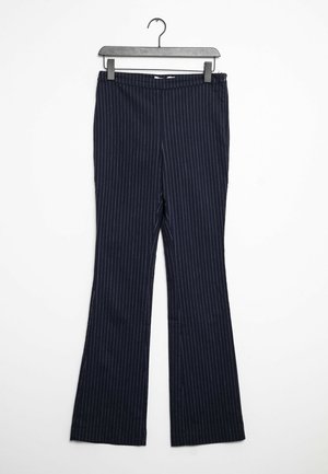 Pantalon habillé bleu marine à fines rayures blanches verticales, présenté suspendu sur un cintre noir contre un fond blanc.